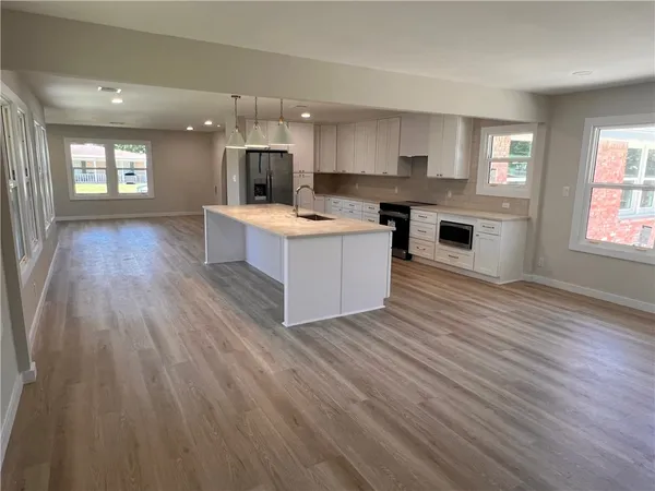 a large kitchen with stainless steel appliances granite countertop a large counter top a wooden floors and a fireplace