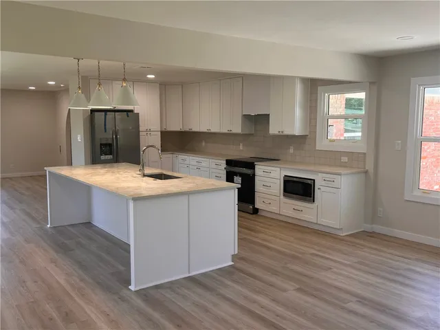 a kitchen with kitchen island stainless steel appliances a stove top oven and a wooden floors