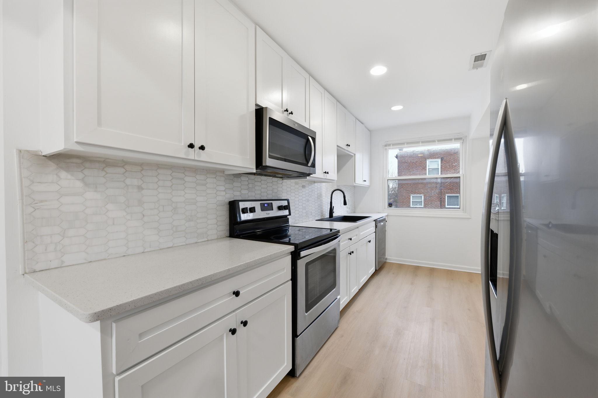 2242 16th Street Northeast Washington, DC 20018 - Photo 9 of 41 a large kitchen with stainless steel appliances granite countertop a sink a stove and a refrigerator
