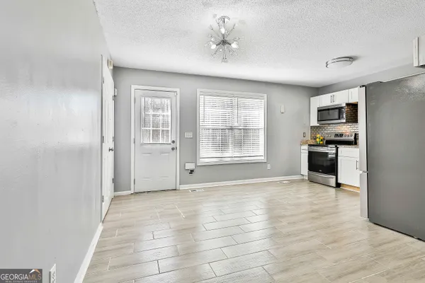 a view of empty room with kitchen and window
