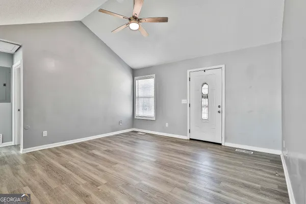 an empty room with wooden floor and windows