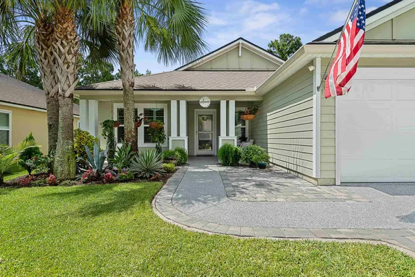 a view of a white house with a small yard and potted plants