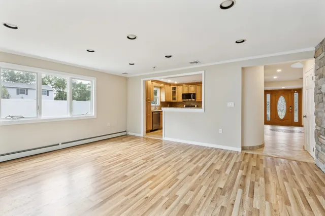 a view of an empty room with window and wooden floor