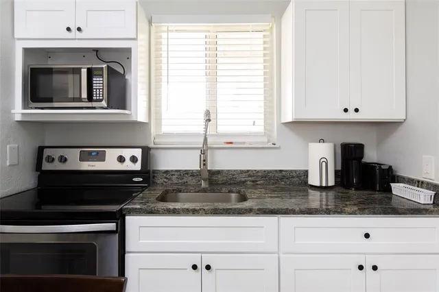 a kitchen with granite countertop a stove a sink and a granite counter tops