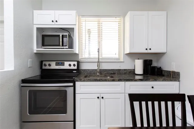 a kitchen with granite countertop a stove top oven microwave and cabinets