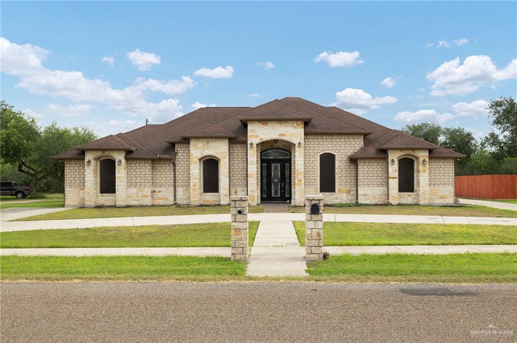 401 Ric Mar Street Edinburg, TX 78541 - Photo 1 of 18 Stone veneer exterior with arched windows and a dark brown shingle roof