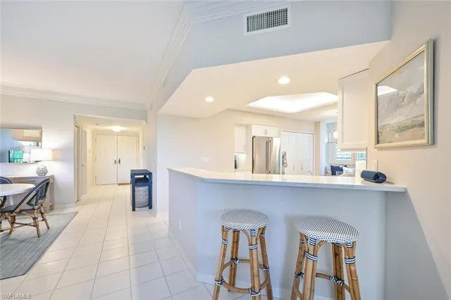 a large white kitchen with cabinets table and chairs
