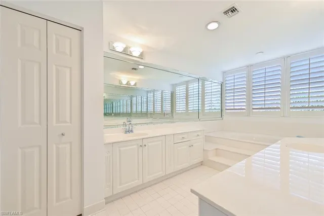 a large white bathroom with a large tub sink and vanity