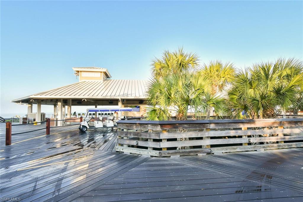 6549 Marissa Loop, Unit 26 Naples, FL 34108 - Photo 32 of 39 a view of patio with table and chairs under an umbrella with wooden floor