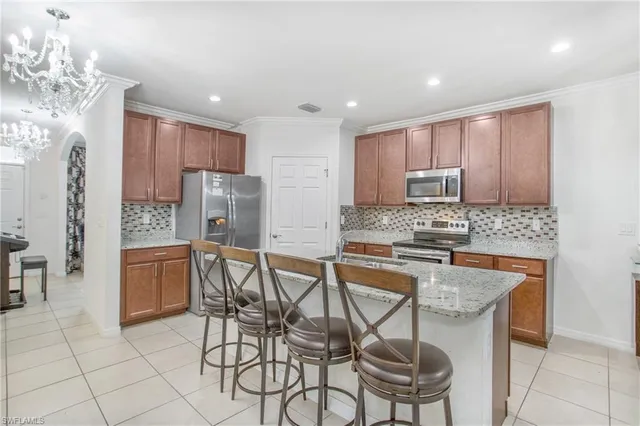 a kitchen with stainless steel appliances granite countertop a stove a sink a microwave a refrigerator and white cabinets