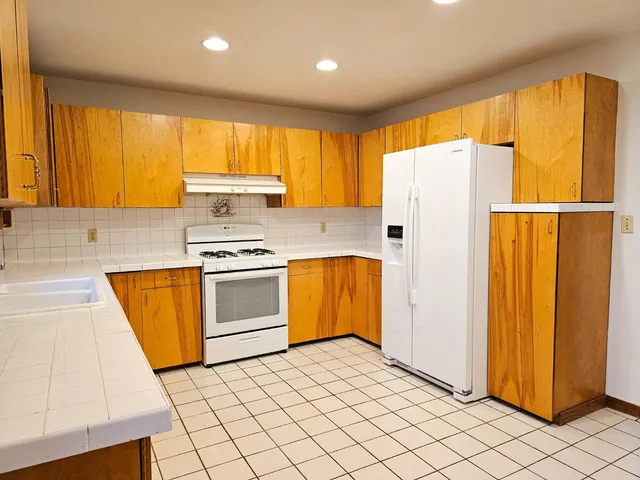a kitchen with a refrigerator a stove top oven a sink and cabinets