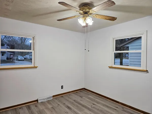 a view of an empty room with chandelier fan