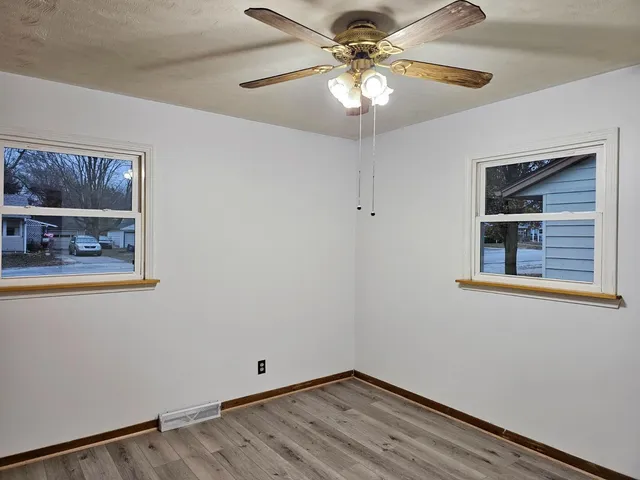 a view of an empty room with chandelier fan