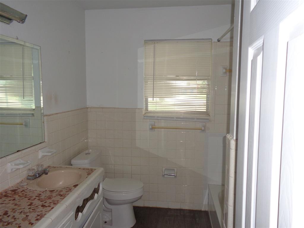 612 South Files Street Itasca, TX 76055 - Photo 21 of 30 Full bath featuring vanity, tile walls, and a wainscoted wall