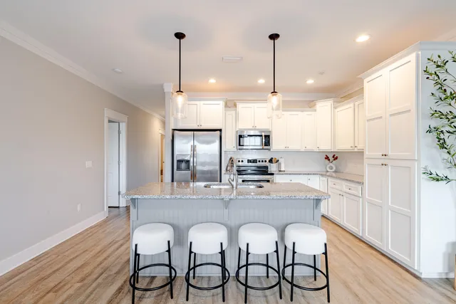 a kitchen with stainless steel appliances granite countertop a sink a stove a refrigerator and island with wooden floor