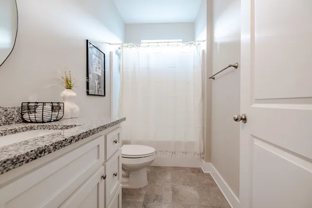 a bathroom with a granite countertop sink a toilet and shower