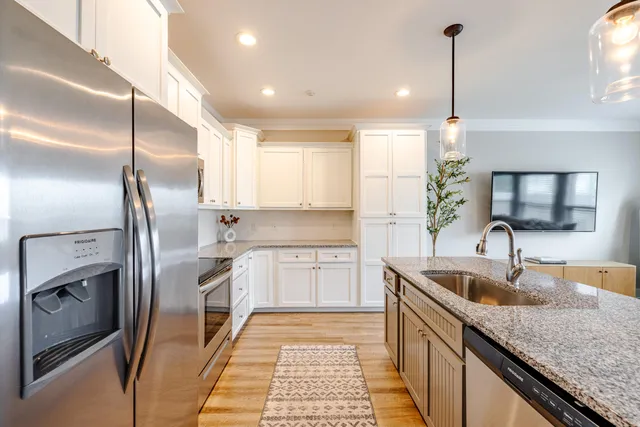 a kitchen with granite countertop a sink a counter space appliances and cabinets