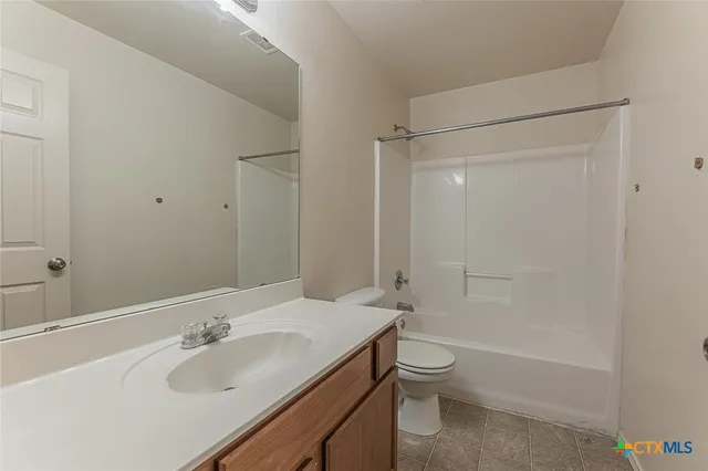a bathroom with a tub sink vanity granite and shower