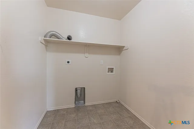 an empty room with a chandelier fan and windows