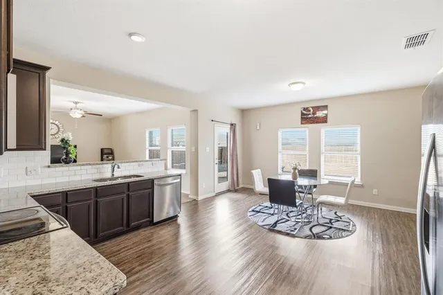 a large kitchen with stainless steel appliances kitchen island granite countertop a stove a sink dishwasher and a refrigerator with wooden floor