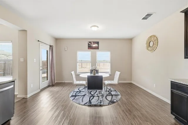 a large living room with stainless steel appliances granite countertop a stove a sink dishwasher and white cabinets with wooden floor