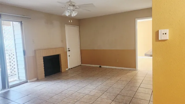 an empty room with chandelier fan and fire place