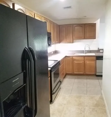 a kitchen with stainless steel appliances granite countertop a refrigerator a sink a stove and oven