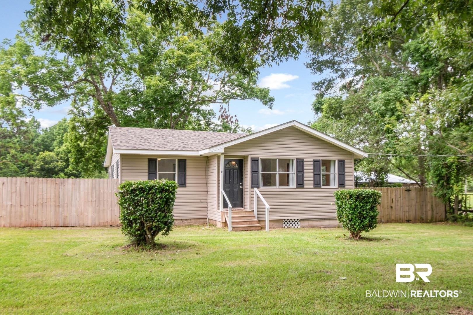 2905A McFarland Road, Unit F Mobile, AL 36695 - Photo 22 of 29 Single-story home featuring light-toned horizontal siding, a fenced yard, a dark entry door, and white porch railings