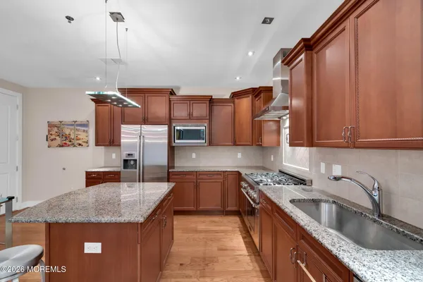 a kitchen with stainless steel appliances granite countertop a sink a stove and a refrigerator