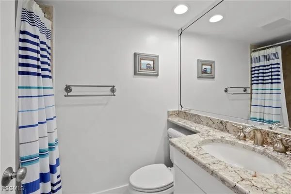 a bathroom with a granite countertop sink toilet and shower