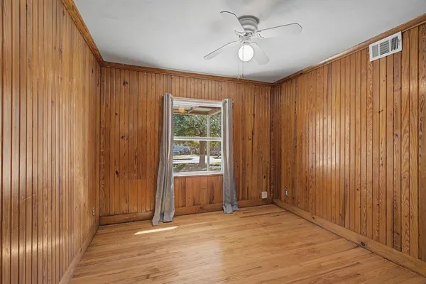 an empty room with windows a ceiling fan and carpet