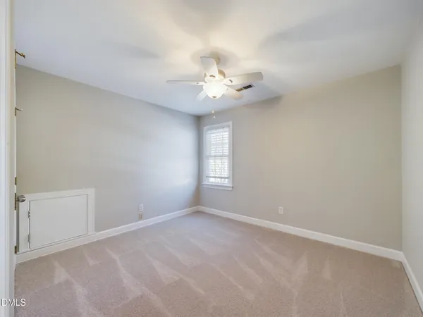an empty room with a window and ceiling fan