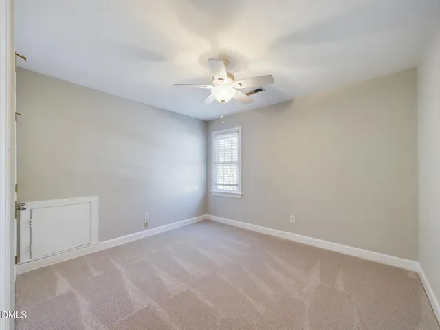 an empty room with a window and ceiling fan