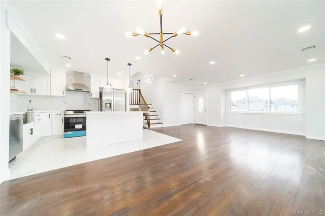 a view of a kitchen with kitchen island a sink wooden floor and a large window