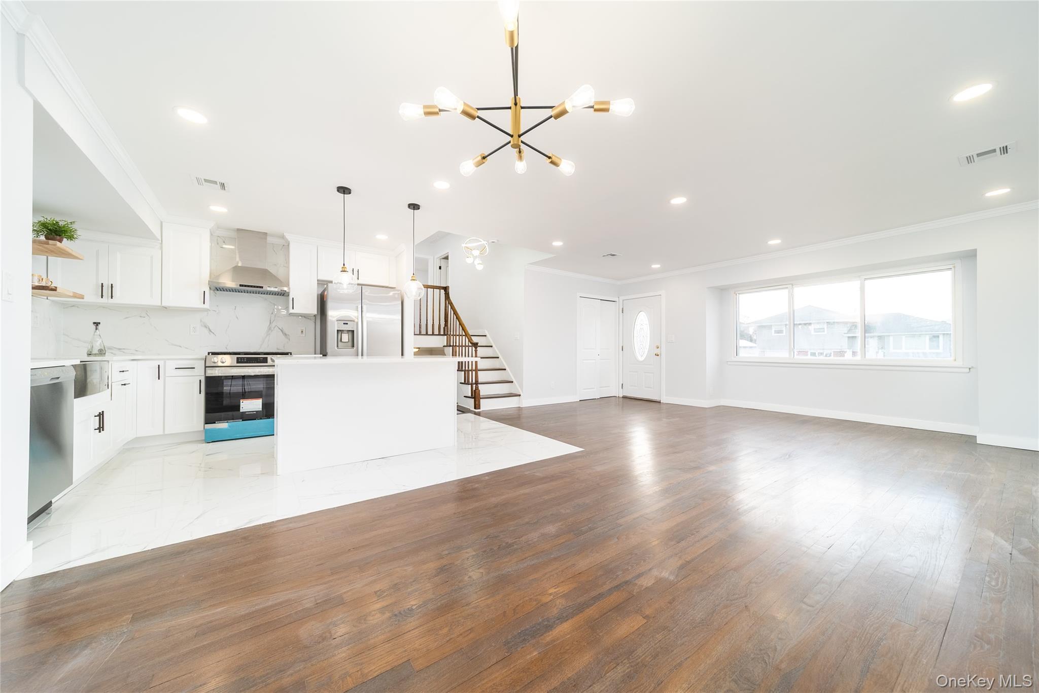 8 Spector Lane Plainview, NY 11803 - Photo 3 of 15 a view of a kitchen with kitchen island a sink wooden floor and a large window