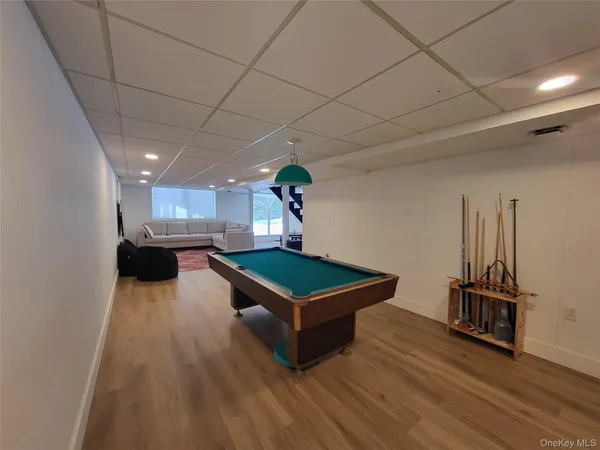 a living room with furniture pool table wooden floor and a ceiling fan
