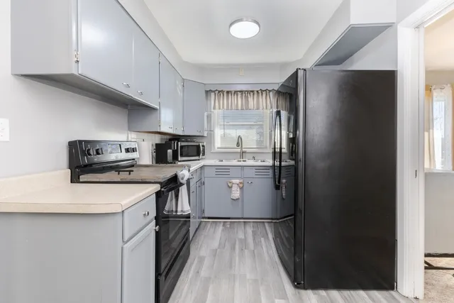 a kitchen with a sink a refrigerator and cabinets