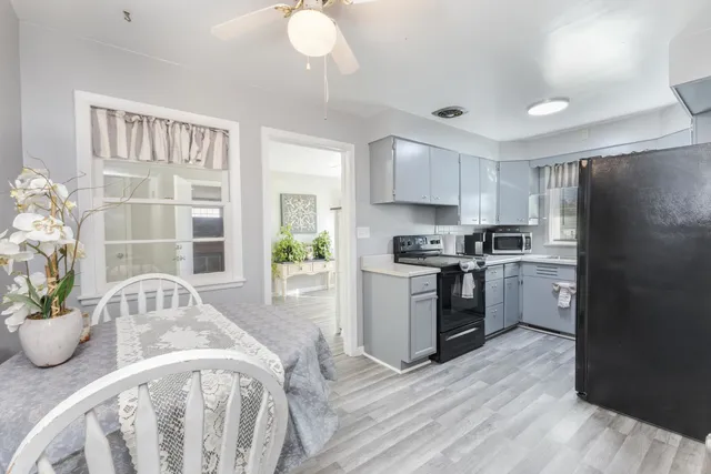 a kitchen with a refrigerator a sink dishwasher a stove and a dining table with wooden floor