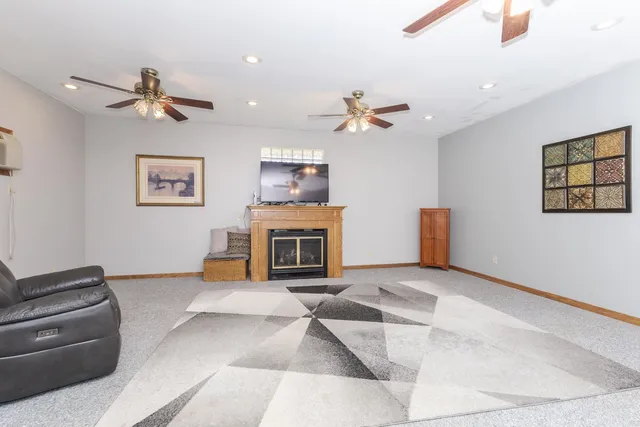 a view of a livingroom with a fireplace a ceiling fan a fireplace and windows