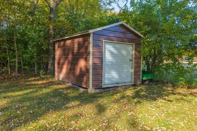 a backyard of a house with plants and large tree