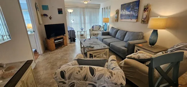 a living room with furniture a flat screen tv and a lamp