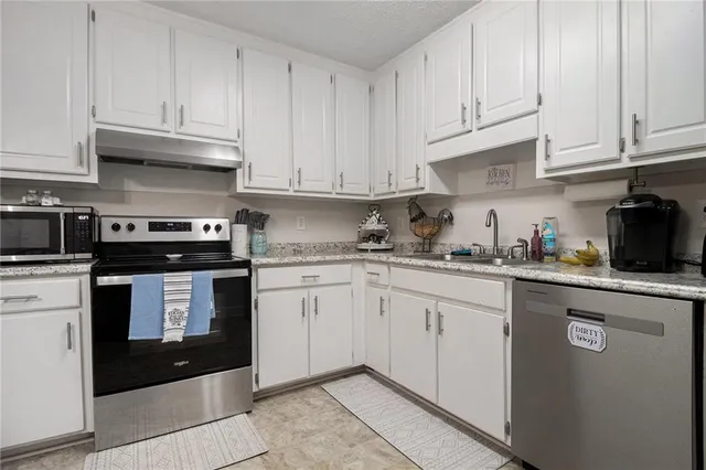 a kitchen with granite countertop white cabinets and stainless steel appliances