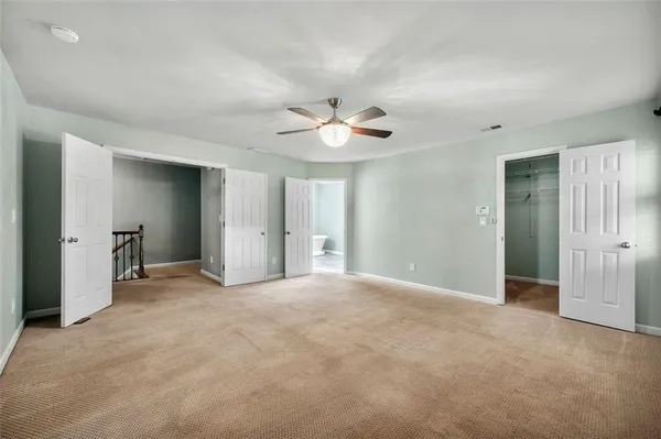 an empty room with closet and a ceiling fan