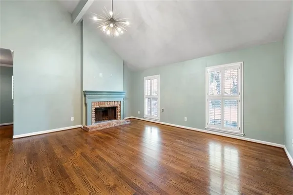 a view of an empty room with wooden floor fireplace and a window