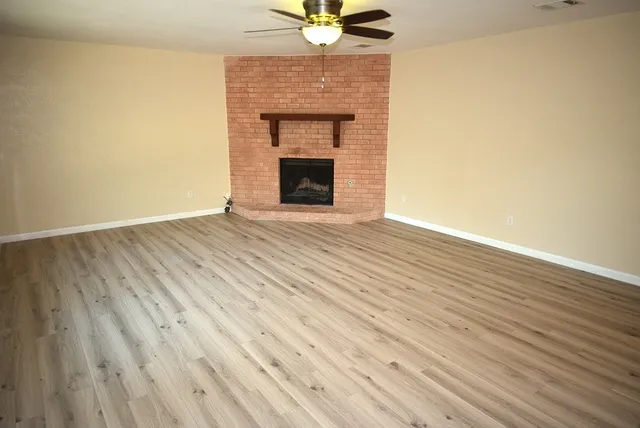 a view of an empty room with wooden floor and a fireplace