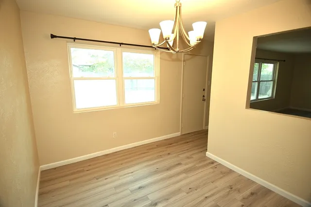 a view of an empty room with wooden floor and a window