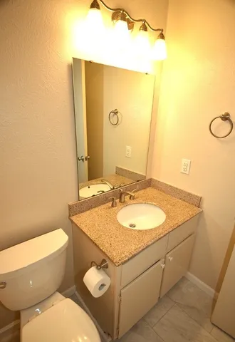 a bathroom with a granite countertop toilet sink and mirror