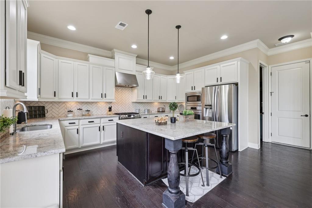 1710 Bramble Bush Way Suwanee, GA 30024 - Photo 13 of 40 a kitchen with stainless steel appliances kitchen island a island in the center and wooden floors