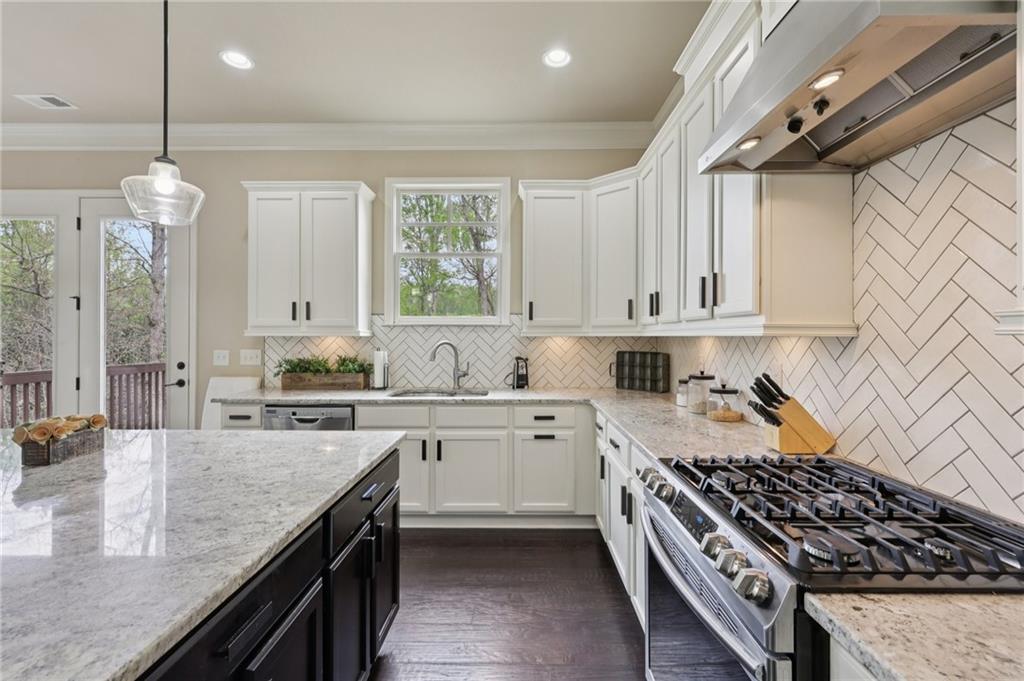 1710 Bramble Bush Way Suwanee, GA 30024 - Photo 14 of 40 a kitchen with kitchen island granite countertop a sink stove and cabinets
