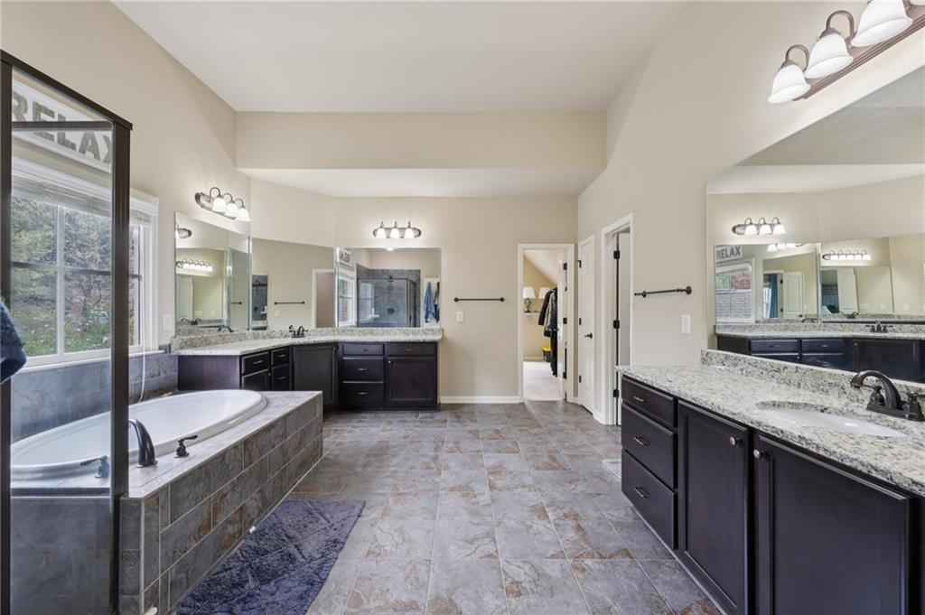 1710 Bramble Bush Way Suwanee, GA 30024 - Photo 19 of 40 a large bathroom with a granite countertop double vanity sink a mirror and a bathtub